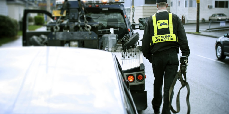 Tow truck driver preparing to tow vehicle